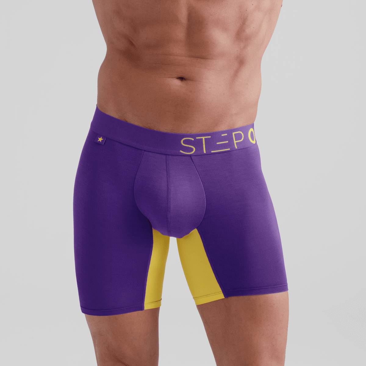 Purple athletic shorts with yellow accents on a gray background - Model:Ivan