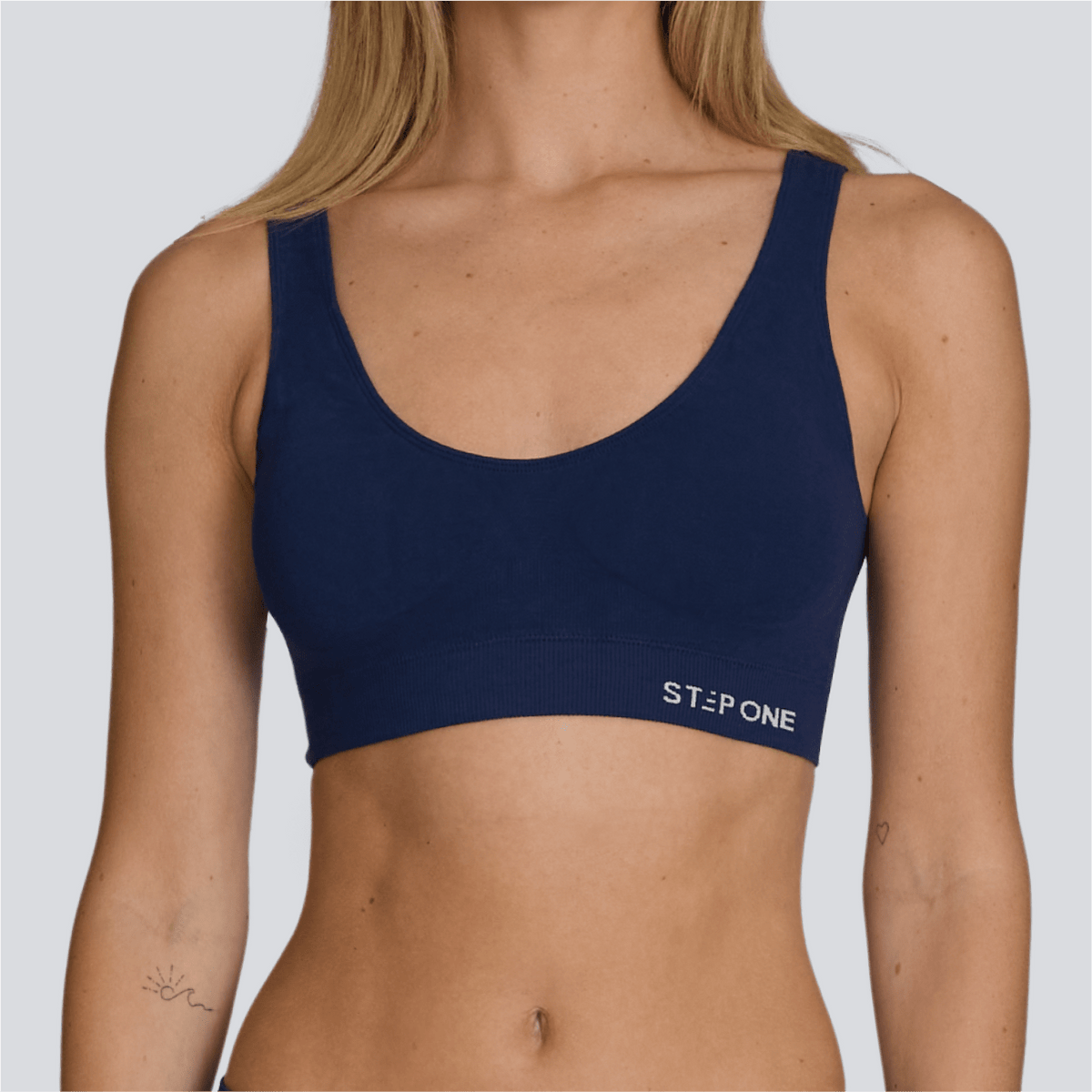 Navy blue sports bra with 'Step One' branding on a plain background  - Model:Emily