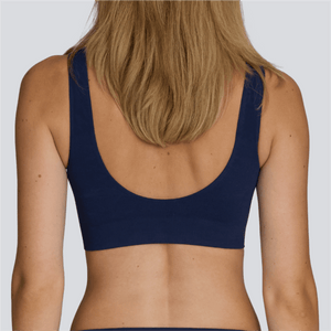 Navy blue sports bra worn by a person on a white background - Model:Emily